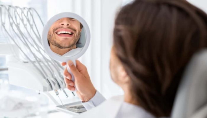 satisfied-patient-checking-smile-at-mirror-in-dent